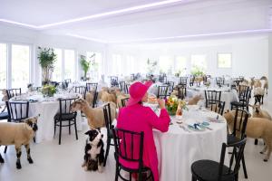 a woman sitting at a table in a room with sheep at Stuckhotel Fettehenne in Ratingen