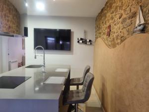 a kitchen with a counter and a tv on a wall at Hauzify I Casa Palamosina in Palamós