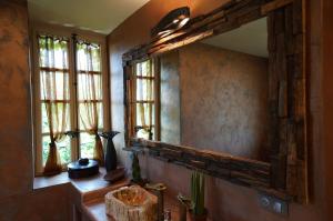 een badkamer met een spiegel, een wastafel en ramen bij MAISON D'HOTES LA GOURGUILLE in Barjac