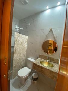 a bathroom with a toilet and a sink and a mirror at Hotel Casa Blanca in Mossoró