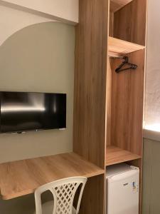 a small kitchen with wooden shelves and a tv at Hotel Casa Blanca in Mossoró