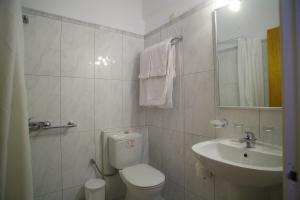 a white bathroom with a toilet and a sink at Athos Hotel in Nydri