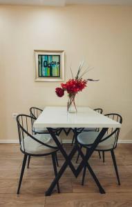a table with chairs and a vase with flowers on it at Luxury Apartment at Myslym Shyri in Tirana