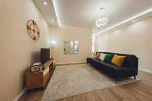 ein Wohnzimmer mit einem schwarzen Sofa und einem TV in der Unterkunft Luxury Apartment at Myslym Shyri in Tirana
