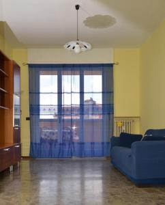 sala de estar con sofá azul y ventana en Casa Vacanza M.V., en Bérgamo