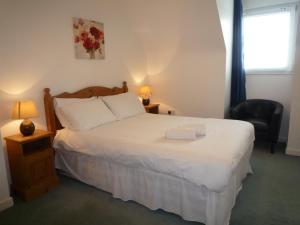 a bedroom with a white bed with a chair and a window at Ballybunion Holiday Homes No 21 in Ballybunion