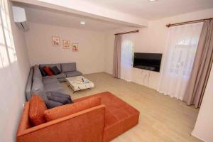 a living room with an orange couch and a television at VillaAnforaSelimiye in Selimiye
