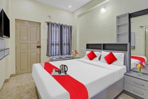 a bedroom with a large white bed with red pillows at Flagship I Care With Greenery Comforts in Tumkūr