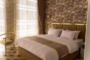 a bedroom with a large bed and a chair at AYNIY Hotel in Samarkand