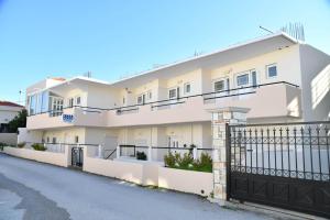 a white building with a gate on a street at Iskas apartments in Ialyssos