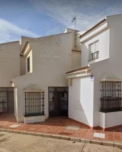 a white building with a gate and a garage at Chalet Chilches Costa 1ª linea PLAYA in Vélez-Málaga