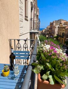 balcone con tavolo e fiori e bottiglia di vino di Casa 900 a Castellammare del Golfo