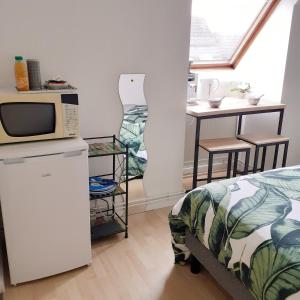 um pequeno quarto com uma cama e um micro-ondas em Maison de la Loue" em Saint-Yrieix-la-Perche