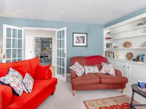 a living room with a red couch and a chair at Beautiful Cottage In Shaftesbury With 3 Bedrooms And Wifi in Shaftesbury