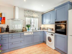 cocina con armarios azules, lavadora y secadora en Beautiful Cottage In Shaftesbury With 3 Bedrooms And Wifi, en Shaftesbury