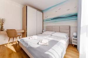 a bedroom with a bed with a painting on the wall at Apartament Clouds SurfingBird Dźwirzyno in Dźwirzyno