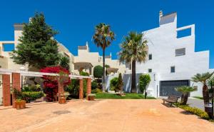 a large white building with trees and palm trees at Estrella de Bahia Casares in Casares