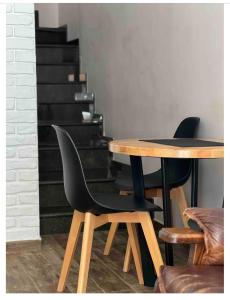 a table with two black chairs next to a staircase at Loft Apartment Kutaisi in Kutaisi