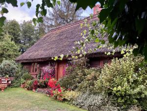 una pequeña casa con flores delante en Chata pod strzechą -Bory Tucholskie, en Świekatowo