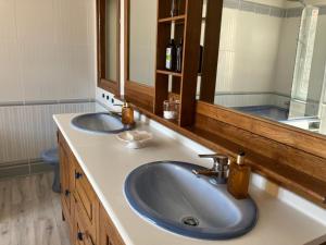 a bathroom with two sinks and a mirror at Villa spacieuse très élégante idéale à la détente in Lamargelle