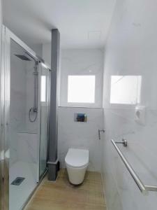 a white bathroom with a toilet and a shower at AGP Globo in Málaga
