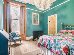 a bedroom with blue walls and a bed and a chandelier at Highbury House in Weston-super-Mare