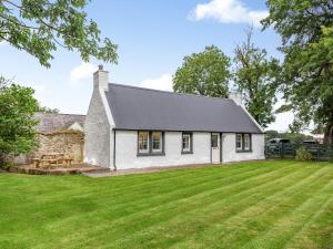 Casa de campo blanca con techo negro en el césped en Balnaha Cottage en Balaldie