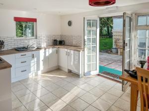 a kitchen with white cabinets and an open door at Owl Lodge in Great Moulton