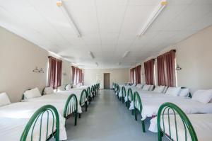 a row of beds in a room with green chairs at Zuikerkop Country Game Lodge in Clocolan