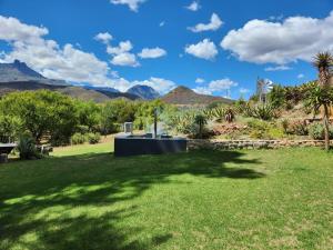 a garden with a fountain and mountains in the background at Sipreslaan Selfsorg Gastehuis in Ladismith