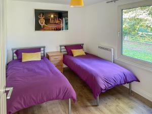 two beds in a room with purple sheets at Owl Lodge in Great Moulton