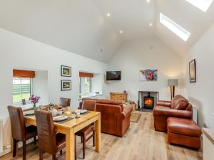 a living room with a table and chairs and a fireplace at Balnaha Cottage in Balaldie