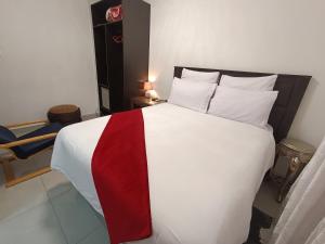 a bedroom with a large bed with a red and white blanket at Manasseh Guesthouse in Gaborone