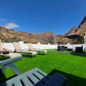 a group of chairs on a lawn with mountains in the background at Casa Camino Tamadaba in Agaete