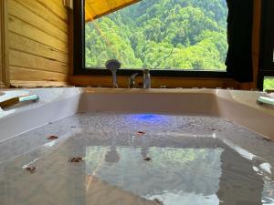 eine Badewanne mit Wasser im Bad mit Fenster in der Unterkunft Meydan Şelale Apart in Çamlıhemşin