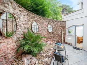 a stone wall with a table and chairs on a patio at Below Deck in Torquay