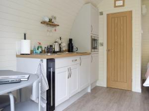 a kitchen with white cabinets and a wooden door at Cain Pod Vip in Llanfyllin