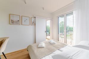 a white bedroom with a bed and a balcony at Apartament SAIL SurfingBird Dźwirzyno in Dźwirzyno