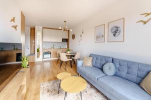 a living room with a blue couch and a table at Apartament SAIL SurfingBird Dźwirzyno in Dźwirzyno