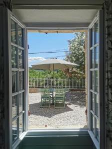 ein Fenster mit Blick auf eine Terrasse mit einem Sonnenschirm in der Unterkunft The Olive Press - Mon Lodge en Provence in Caromb