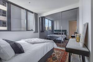 a bedroom with a large bed and a mirror at Premium Albert Park Grand Prix Apartment by Ready Set Host in Melbourne