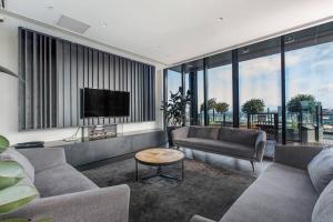 a living room with two couches and a tv at Premium Albert Park Grand Prix Apartment by Ready Set Host in Melbourne