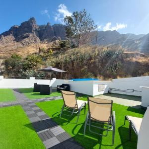 a patio with grass and chairs with mountains in the background at Casa Camino Tamadaba II (bottom home） in Agaete