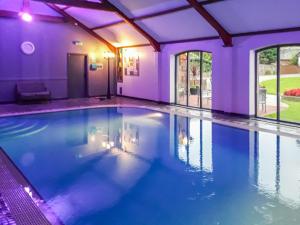 a swimming pool in a house with purple lighting at Stackgarth in Gilcrux