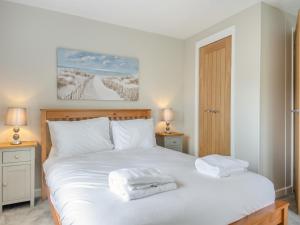 a bedroom with a white bed with two towels on it at Baythorn End in Antingham