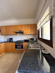 a kitchen with wooden cabinets and a sink at Relaxing Gateway in Limassol in Episkopi Limassol