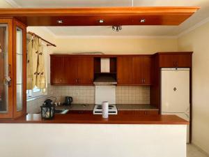 a kitchen with wooden cabinets and a white refrigerator at Sea view Sarande in Sarandë