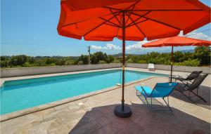 a pool with two umbrellas and a blue chair and a table at Amazing Home In Giuncaggo With Wifi in Aléria
