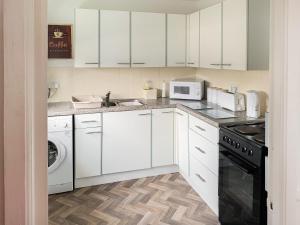 a kitchen with white cabinets and a stove top oven at Sunny Prestatyn Apartment in Prestatyn