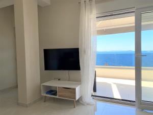 a living room with a tv and a large window at Apartment Azuri in Okrug Donji